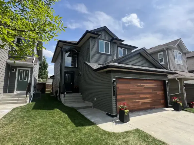 Dark painted Calgary home exterior with wood garage door and landscaped front yard