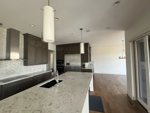 Finished kitchen in the same Calgary home with dark cabinetry light counters and freshly painted walls