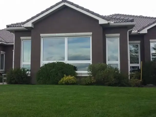 Large brown stucco home with light trim after exterior repainting by Dynamic Painting