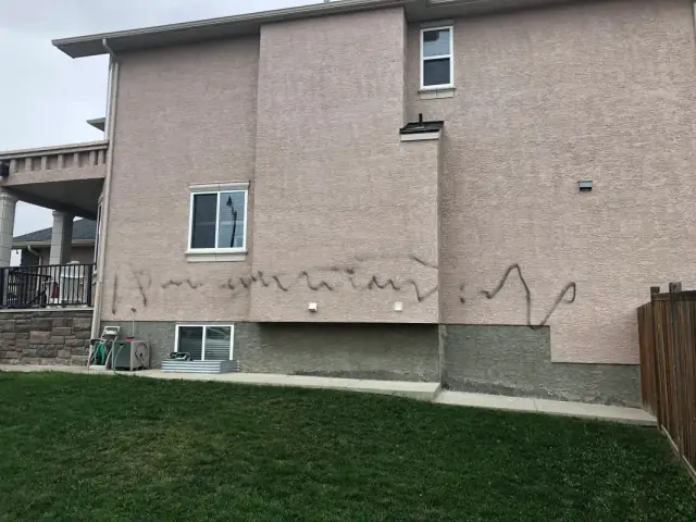 Stucco wall with graffiti damage before exterior repair and repainting