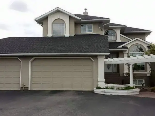 Large neutral stucco home with three-car garage and bright white exterior accents