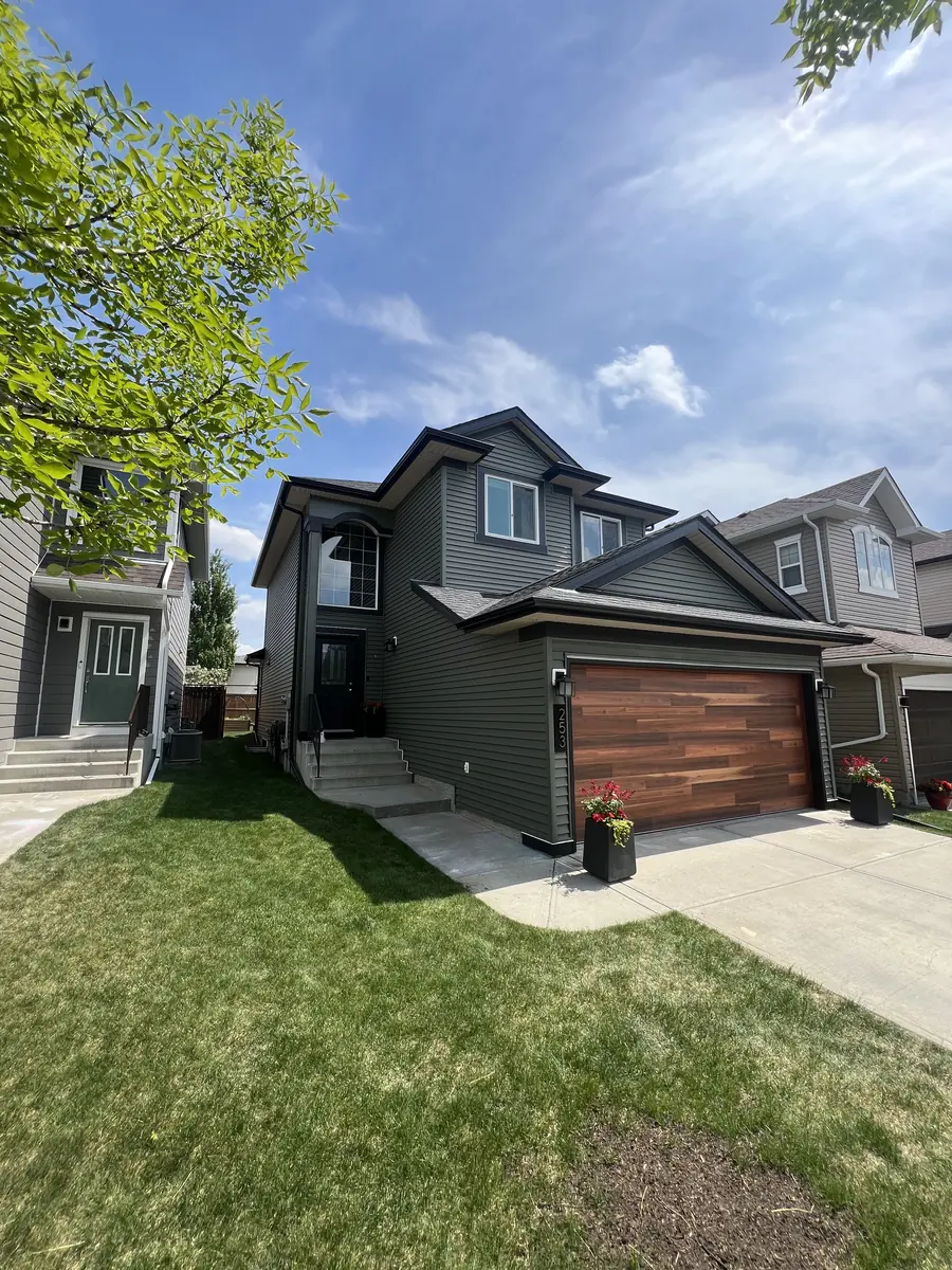 Dark painted Calgary home exterior with wood garage door and landscaped front yard