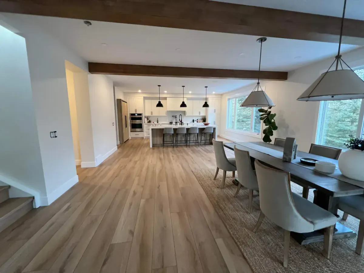 Finished Calgary open-concept living dining and kitchen space with painted walls and wood ceiling beams