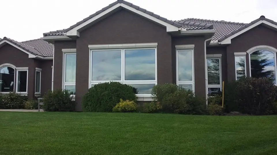 Large brown stucco home with light trim after exterior repainting by Dynamic Painting