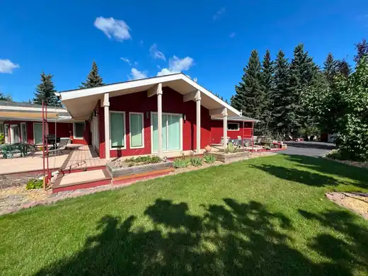 Finished red wood siding exterior with cream trim and covered backyard patio