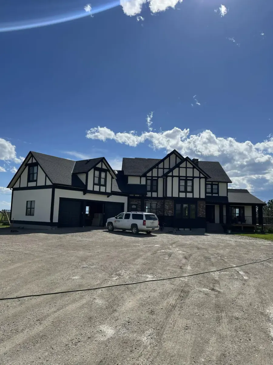 Large black and white stucco estate with dramatic dark trim and Tudor-inspired exterior detailing