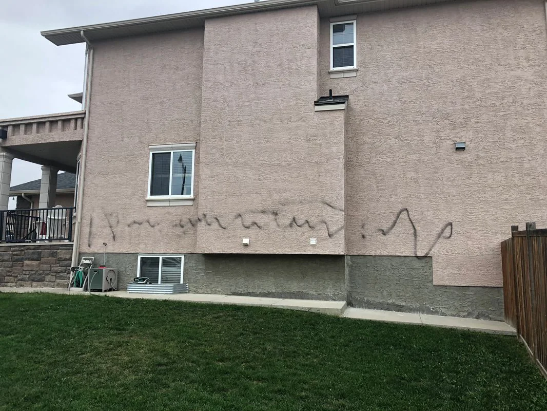 Stucco wall with graffiti damage before exterior repair and repainting