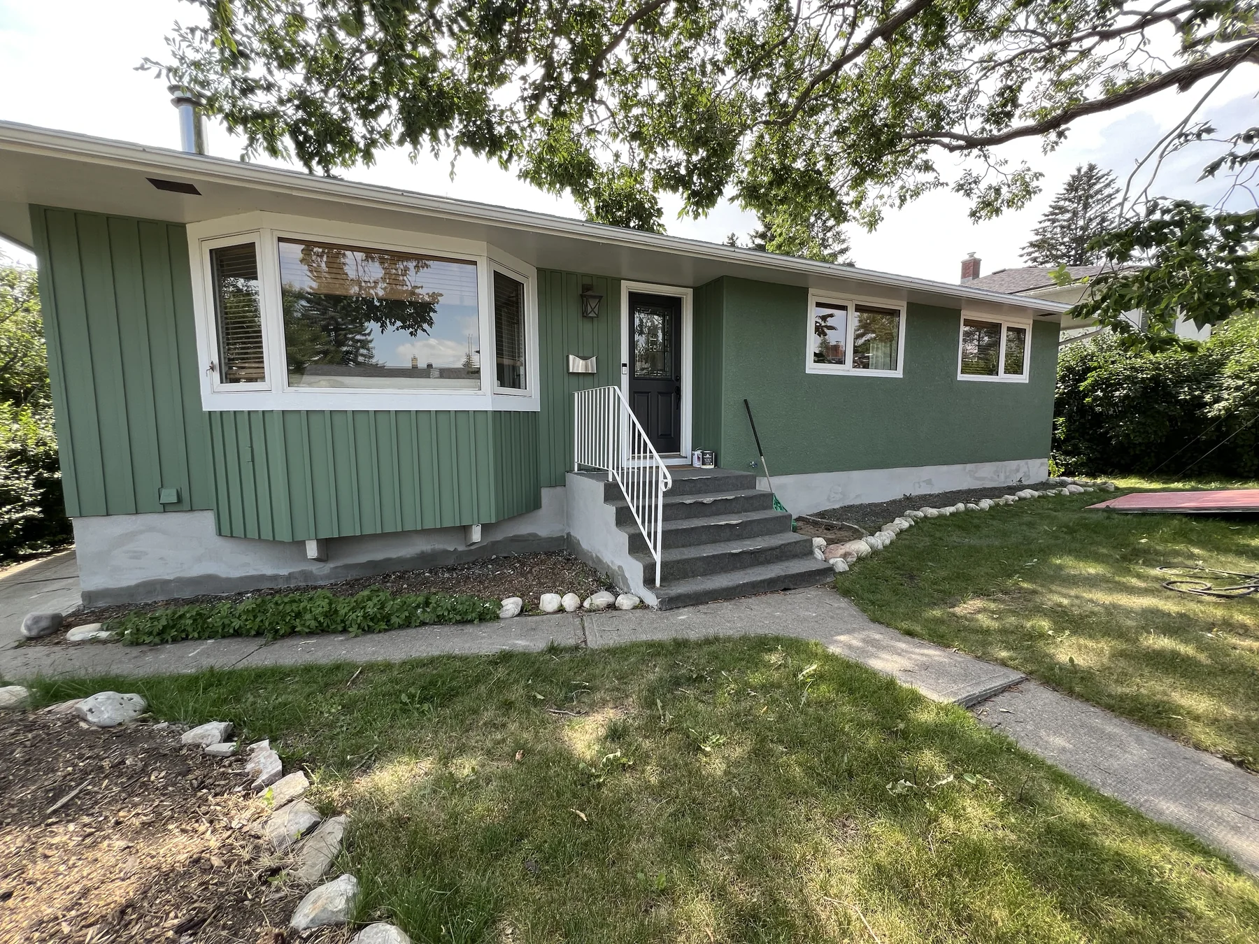 Green Calgary bungalow with freshly painted stucco and coordinating exterior siding