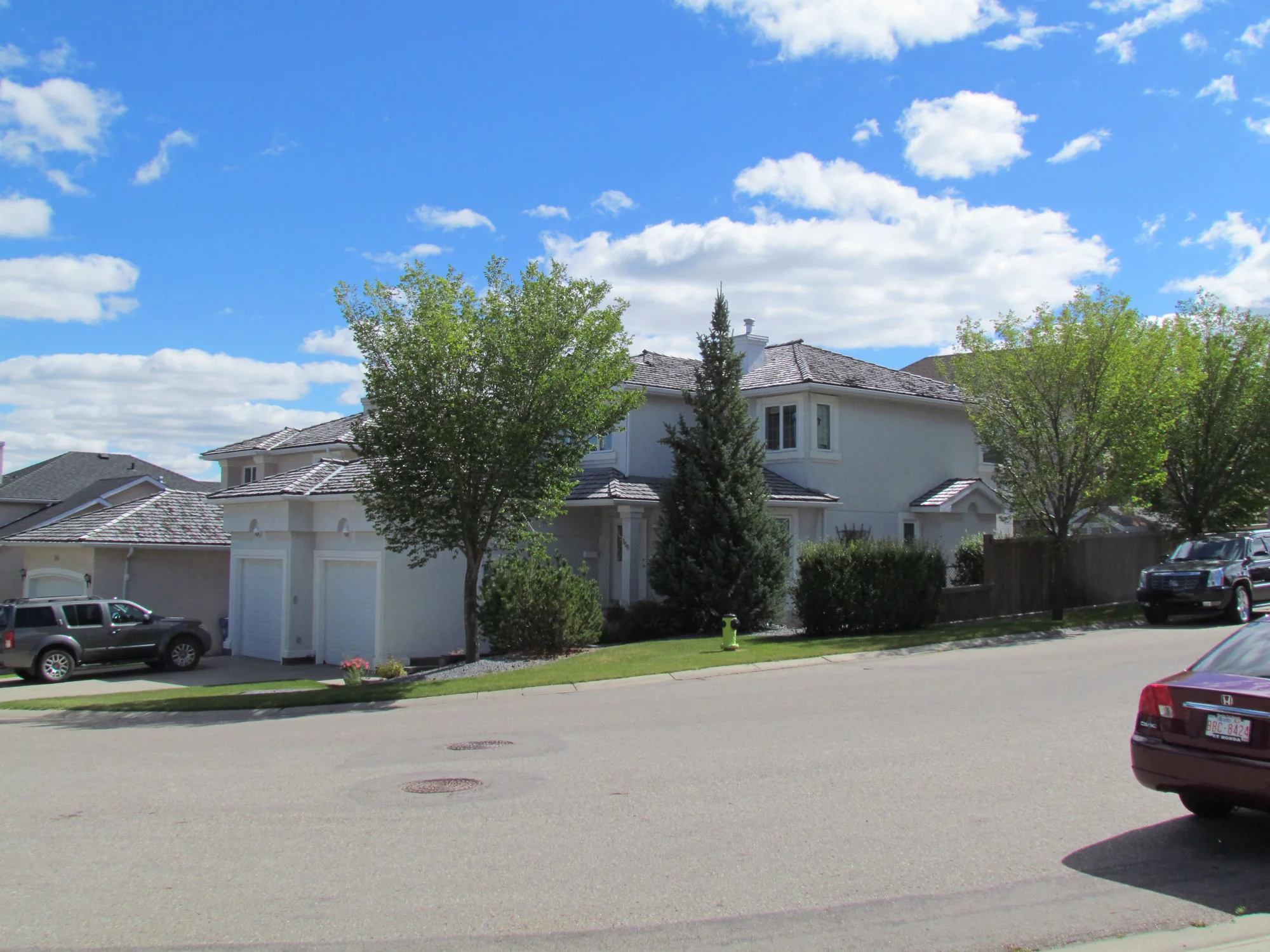 Large light-coloured stucco home before a dramatic exterior colour transformation