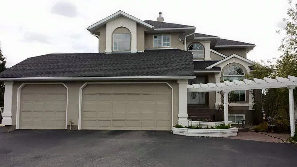 Large neutral stucco home with three-car garage and bright white exterior accents