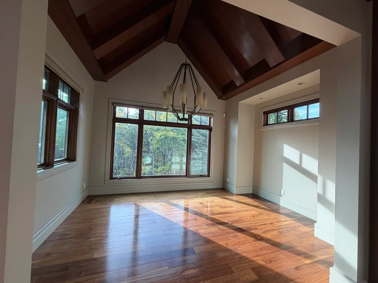 Beamed main-floor room before repainting, with wood window frames, a wood ceiling and existing light walls