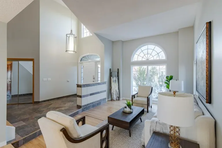 Completed Calgary vaulted living room with neutral walls, an arched window and white window trim