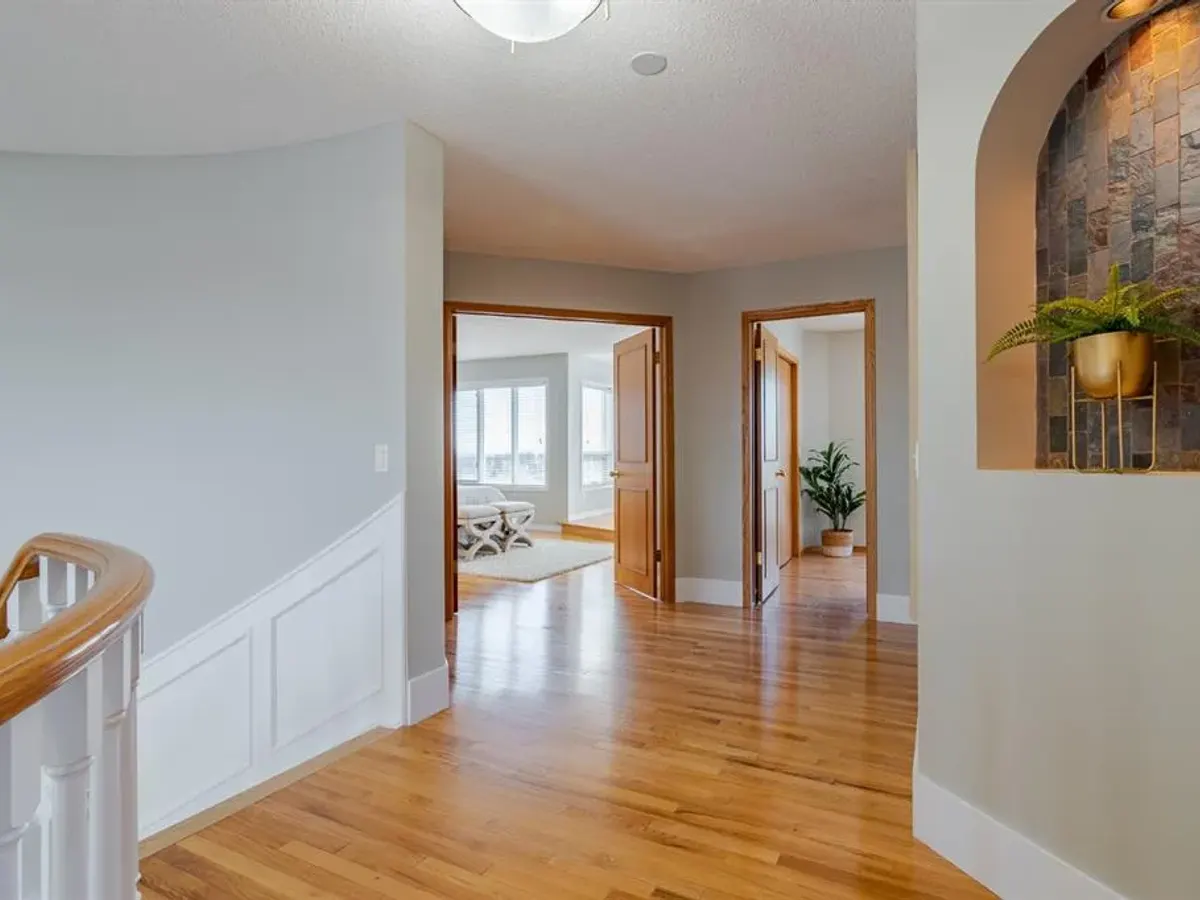 Pale painted hallway walls with white trim, wood flooring and open doorways in a Dynamic Painting interior